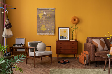 Creative composition of cozy living room interior with wooden sideboard, coffee table, brown sofa, yellow wall, kilim rug, orange lamp, vase with leaves and personal accessories. Home decor. Template.