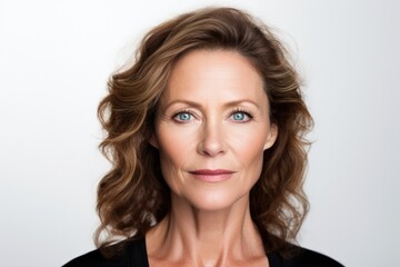 Fototapeta premium Close-up portrait of an attractive middle aged woman with toothy smile wearing blazer while standing at isolated dark background. Copy space. Studio shot.