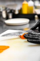Close-up of hand sushi chef in gloves slices fresh salmon fish fillet at sushi bar.