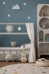 Aesthetic composition of cozy kid room interior with stylish bed, blue wall, braided pouf, round...