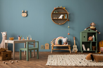 Cozy composition of kid room interior with round shelf, gray desk, green armchair, blue wall, braided rug, plush toys, braided basket, block toys and personal accessories. Home decor. Template. - obrazy, fototapety, plakaty