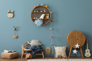 Creative composition of kids room interior with blue wall, rattan sideboard, armchair, pillows,...