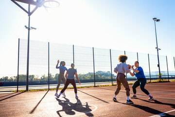 Diverse group of young woman having fun playing basketball outdoors.