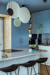 Interior design of kitchen interior with marble kitchen island, blue wall, black chokers, bowl with...