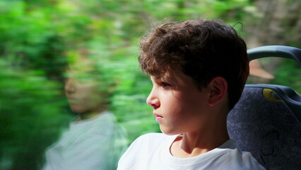 close-up of contemplative preteen boy aboard bus, engrossed in scenic journey through window. Young...