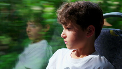 close-up of contemplative preteen boy aboard bus, engrossed in scenic journey through window. Young...