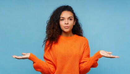 Young confused puzzled latin professional woman, doubtful uncertain hispanic female model student wearing orange sweater standing shrugging thinking of difficult choice isolated 