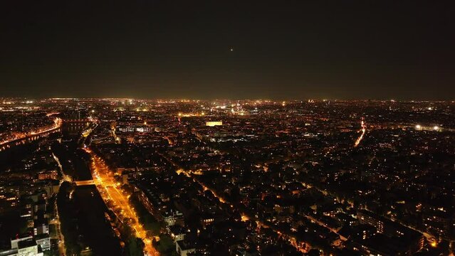 Aerial descending footage of metropolis at night. Illuminated streets and buildings glowing into dark. Paris, France
