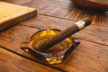 Puro cubano de tabaco sobre un cenicero en una mesa de madera