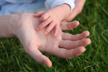 Gros plan sur la main d'un bébé dans la main de sa maman