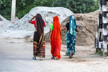 three women walking in the streets with typical Indian clothing, with many colors