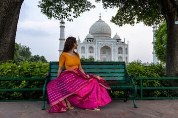 Woman looks at the imposing Taj Mahal in Agra, India, with its wonderful architecture on a cloudy...