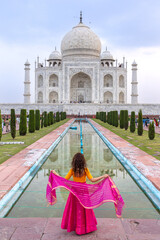 Woman looks at the imposing Taj Mahal in Agra, India, with its wonderful architecture on a cloudy day