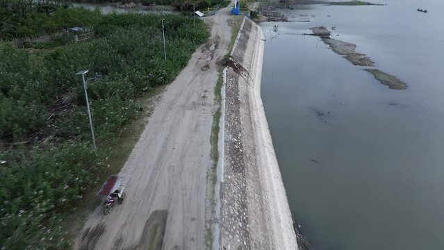 Aerial view of bentor (becak motor) riders speeding on the road across Lake Limboto. aerial view of a lake experiencing drought