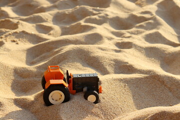 Toy tractor on the sand, closeup of photo with selective focus