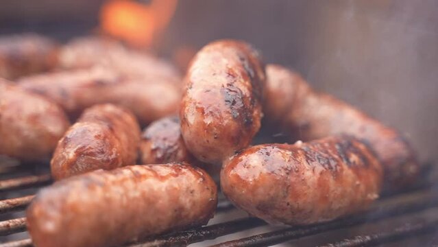 Suggestive closeup locked down shot of delicious scorched sausages on the grill during a BBQ barbecue. Smoke.  Summer party.