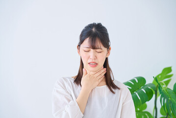 喉に違和感を感じている若い女性