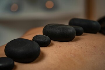 Female customer is receiving a relaxing spa treatment of hot stone massage