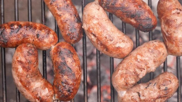 Overhead flat lay shot of delicious sausages on the grill during a BBQ barbecue outdoors. Zoom out. Summer party.
