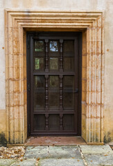Fototapeta na wymiar Old wooden door surrounded by carved stone in Spanish architecture style home