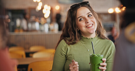 Girl friends, talk and smoothie in cafe, green drink and happy for health, nutrition and juice with...
