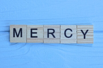 word mercy made from wooden gray letters lies on a blue background