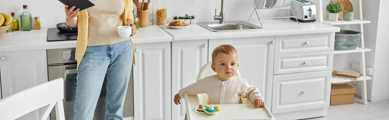 little girl sitting in baby chair near rattle toy near mom with notebook and coffee cup, banner