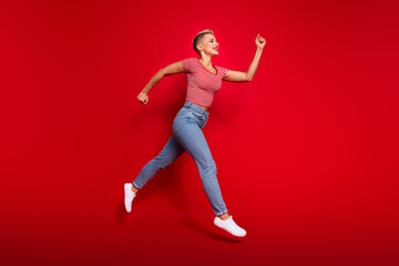 Full length photo of purposeful motivated girl wear stylish clothes running empty space isolated on red color background