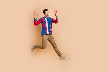 Fototapeta na wymiar Full body size photo of crazy man jumping running to entertainment selfie shooting for fans account isolated on beige color background