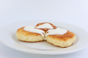 Delicious, ruddy cheesecakes covered with sour cream on a white plate.