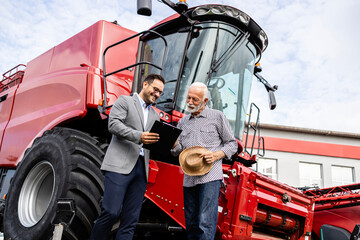 Tractor dealer and farmer negotiating about combine harvester purchase. © littlewolf1989