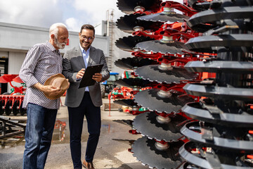 Farmer and tractor dealer discussing about harrow and farming equipment.