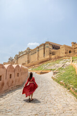 Woman at the entrance to Amber Fort in daytime with cloudy sky, near Jaipur, The Pink City,...