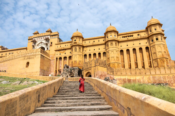 Woman at the entrance to Amber Fort in daytime with cloudy sky, near Jaipur, The Pink City,...