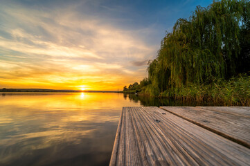 Sonnenuntergang am Süßen See mit Holzsteg und grünem Uferbereich im Vordergrund
