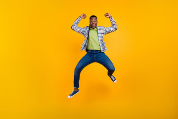 Fototapeta na wymiar Full body size photo of crazy strongest manager guy raised fists up jumping in office as the best isolated on yellow color background