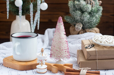 New Year's hot drink with spices on a white knitted blanket. Festive home decoration, Christmas trees and burning candles