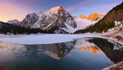 Sunrise in winter mountains. Mountain reflected in ice lake in morning sunlight