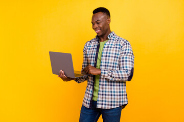 Photo of young perspective manager happy guy working with clients in online using his computer isolated on yellow color background - obrazy, fototapety, plakaty