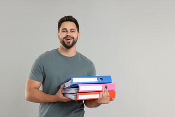 Happy man with folders on light gray background, space for text