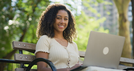 Young black woman working on laptop computer at a park