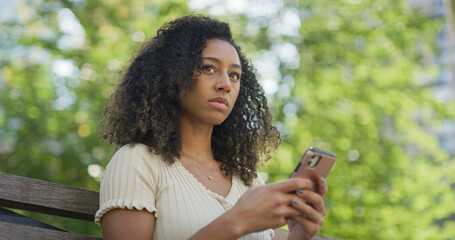 Young black woman using smartphone at a park