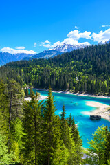 Small island in the middle of Cauma Lake (Caumasee) with crystal blue water in beautiful mountain landscape scenery at Flims, Graubuenden - Switzerland