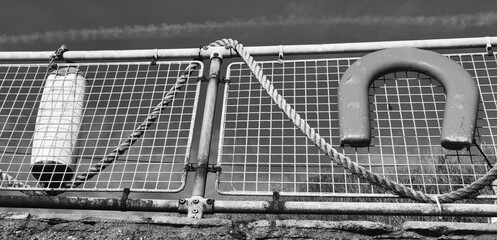 Old rope, fence and boat buoy next to water
