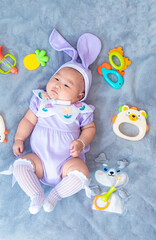 Fototapeta premium Baby boy in bunny costume,Cute baby Easter bunny. Little baby boy with bunny ears and Easter eggs in wicker basket in white fur. Symbol of Easter holiday, birth, spring, religion