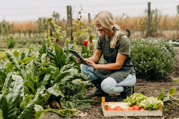 Happy woman is using digital tablet in the garden.