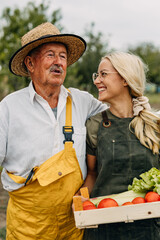 Grandfather and granddaughter harvesting together in the garden