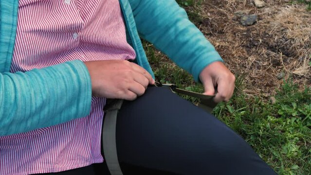 A girl places a tourniquet on her leg as part of first aid training. Using a medical tourniquet to stop bleeding. Close-up