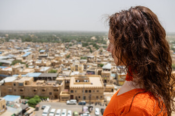 Woman looks down on the city from the Jaisalmer Fort in Rajasthan, India. The golden city of the Thar desert