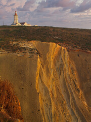 Espichel cape lighthouse sitting on top of a cliff during sunset. Sesimbra, Setubal, Portugal.